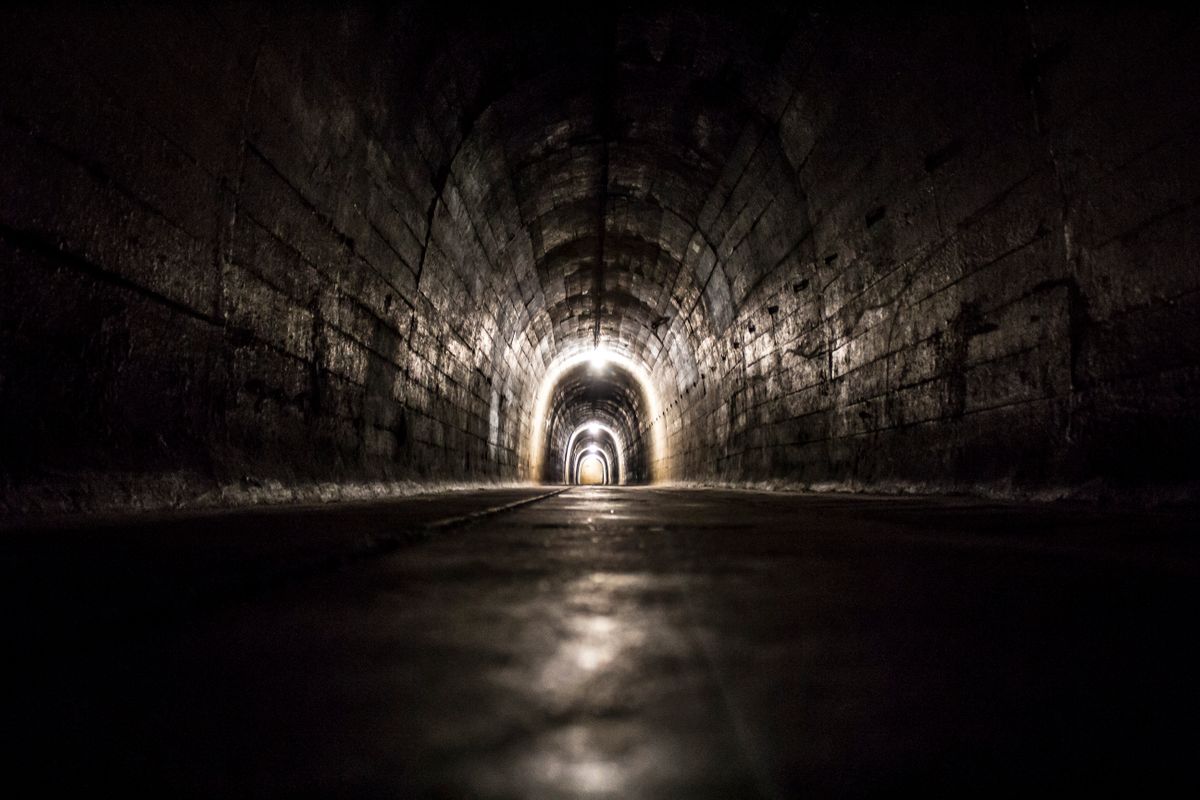 Dark underground concrete tunnel with low visibility illustrating confined space hazards