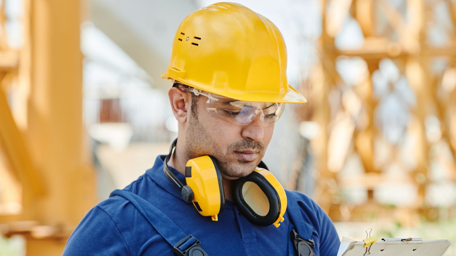 Construction worker wearing a hard hat, safety glasses, and hearing protection on an active job site
