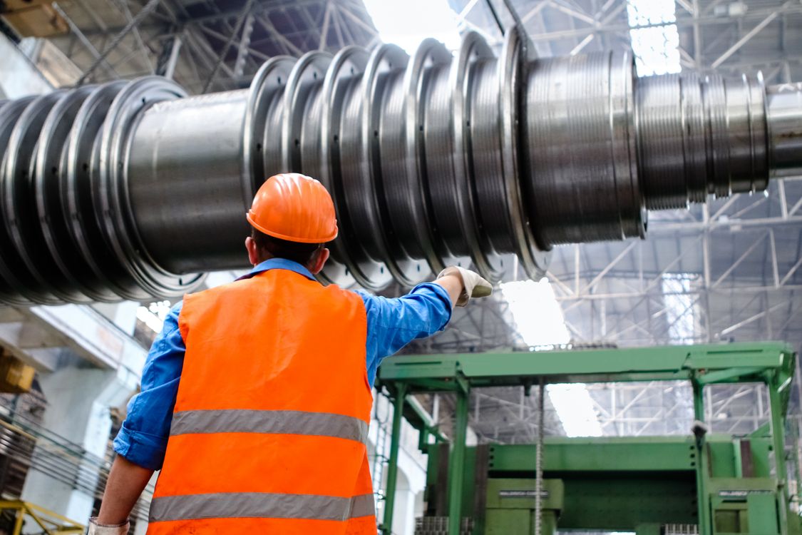 Industrial worker in a hi-vis vest checking hazards near heavy factory machinery