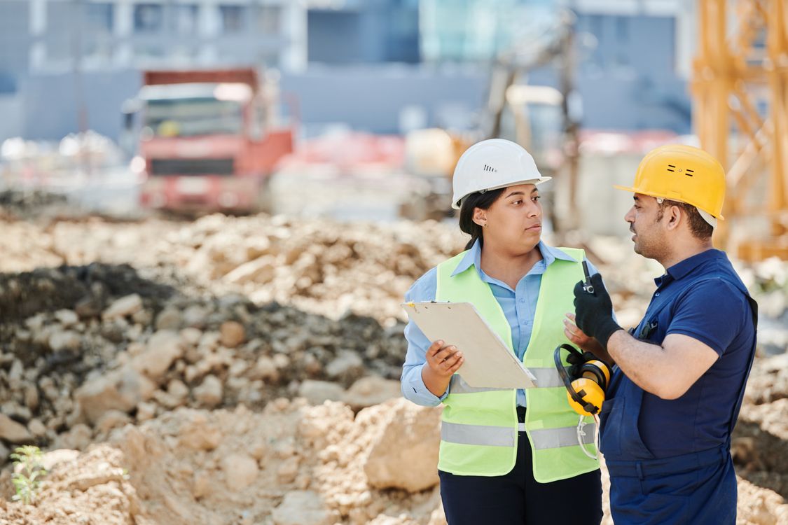 Site supervisor and worker in hard hats discussing safety on a construction site