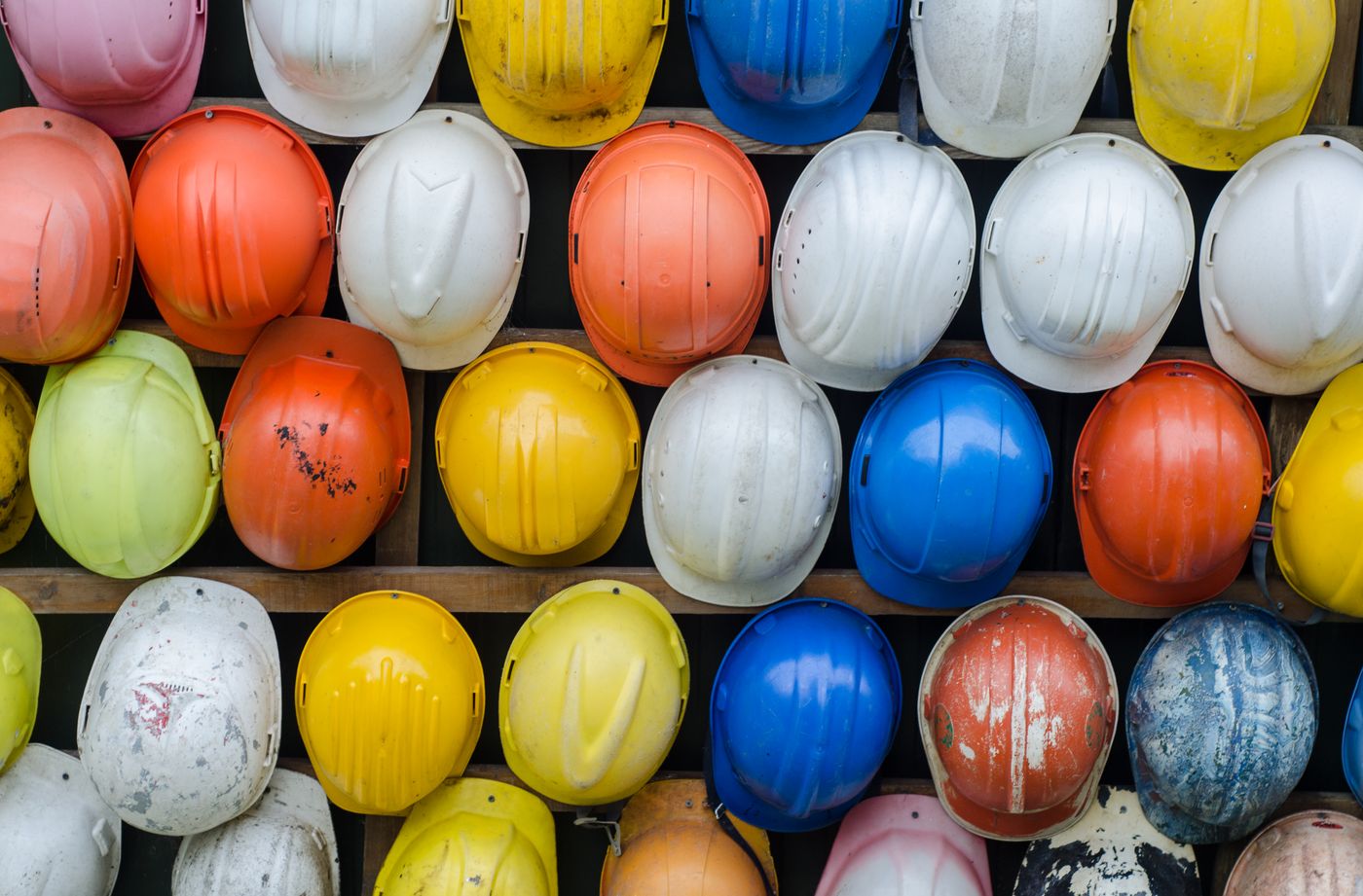 Rows of construction hard hats hung on a wall at a jobsite
