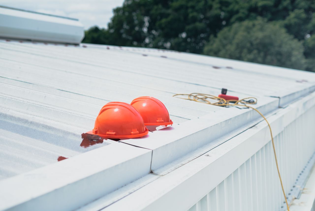 Hard hats staged on a low slope metal roof, the job that makes crews ask: when is fall protection required