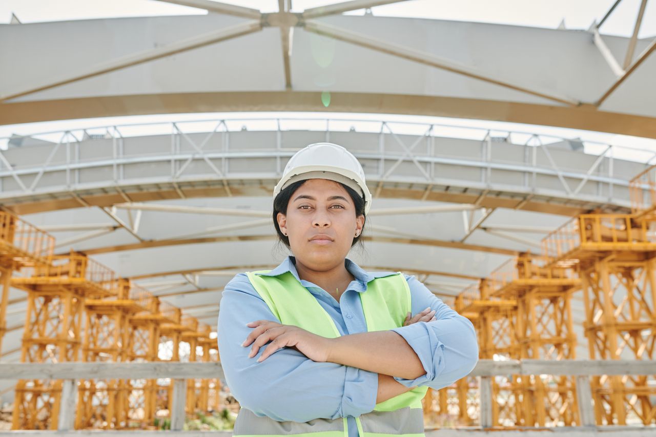 Safety professional in a hard hat and high visibility vest inspecting a construction site