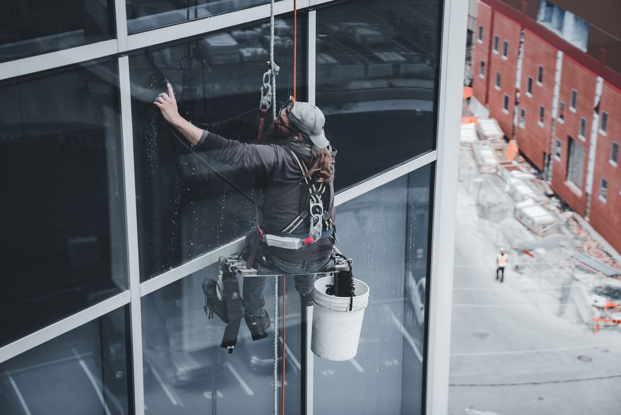 Worker suspended at height in a personal fall arrest harness on a building facade