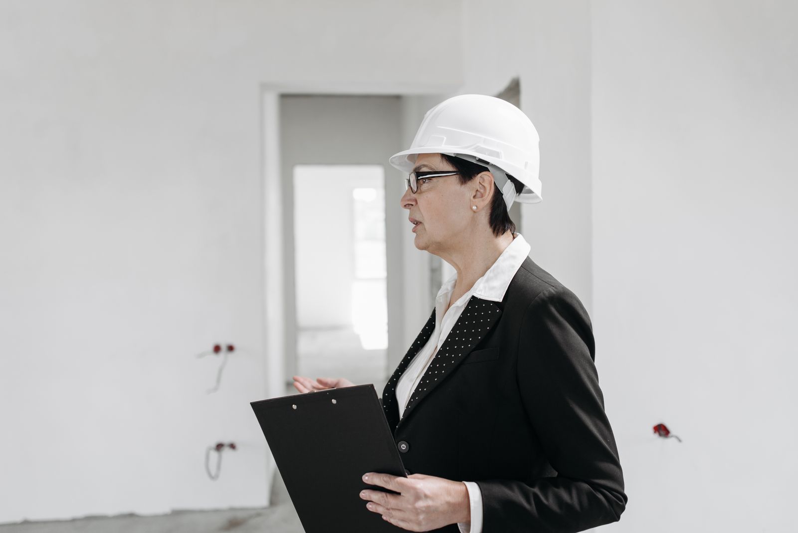 Safety consultant in a hard hat with a clipboard walking an unfinished building