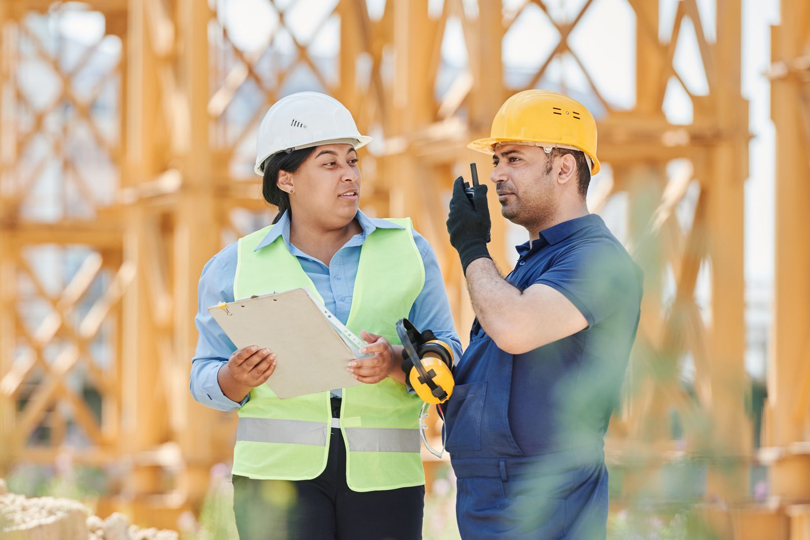 Two construction workers in hard hats talking through a plan on a jobsite